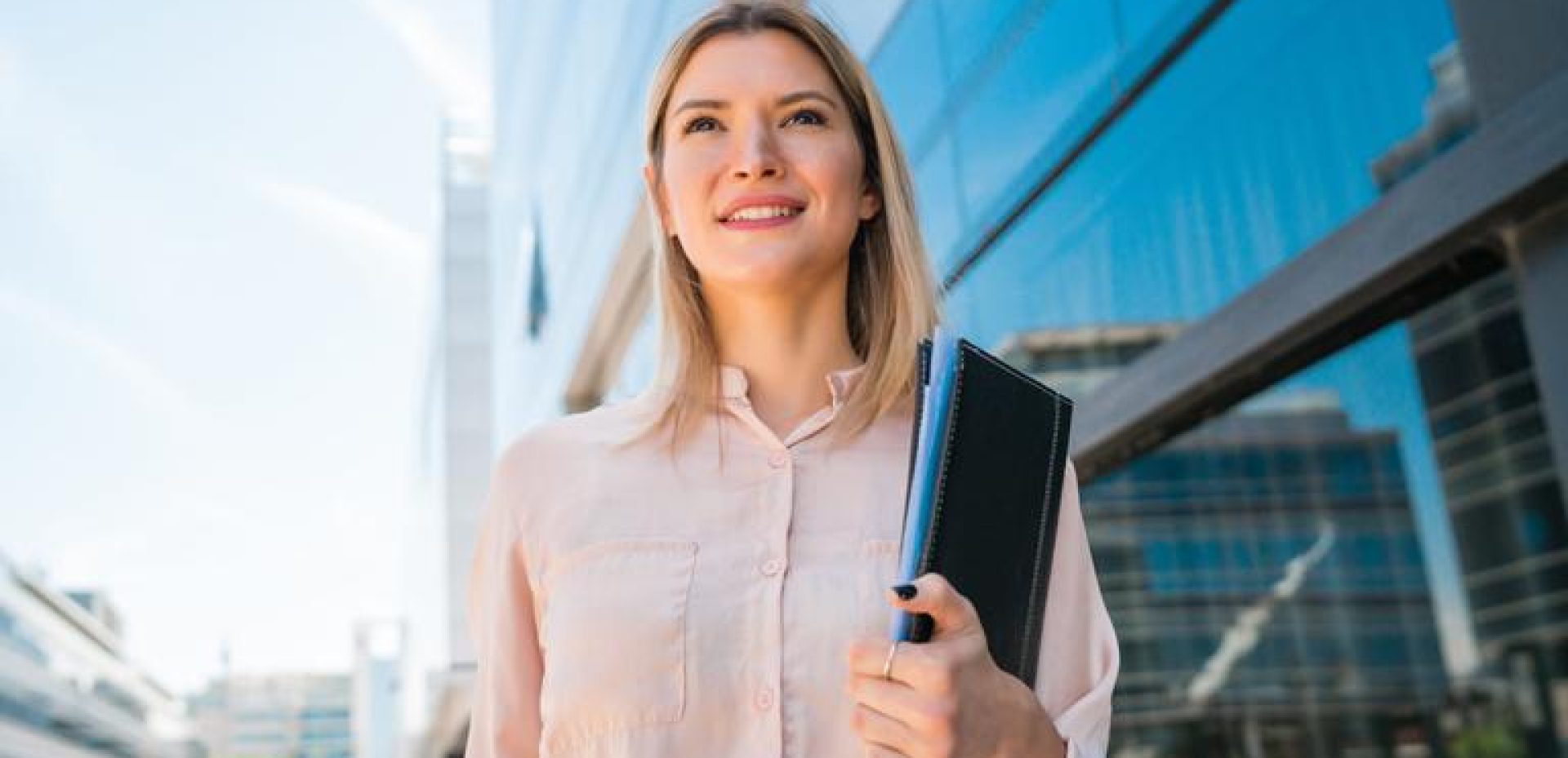 Portrait of young business woman standing outside office buildings. Business and success concept.